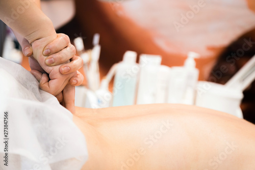 Young beautiful woman having back massage in spa salon. Massage techniques.