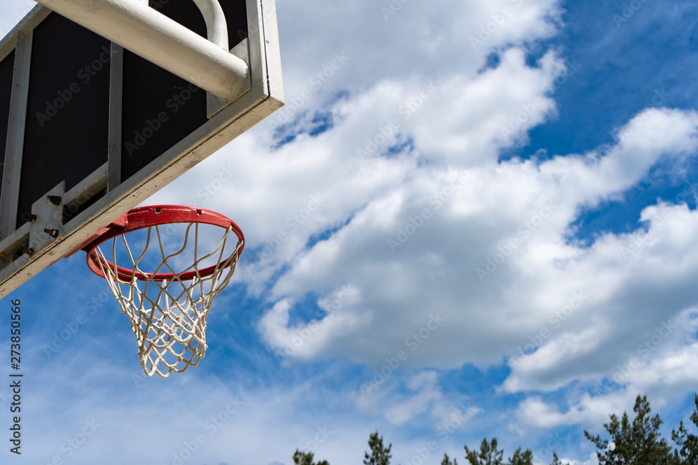 Basketball backboard with a ring on the street and blue sky