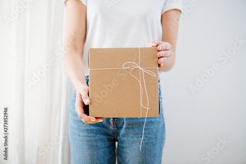 Portrait of a woman in casual clothes vertically holding postal cardboard box