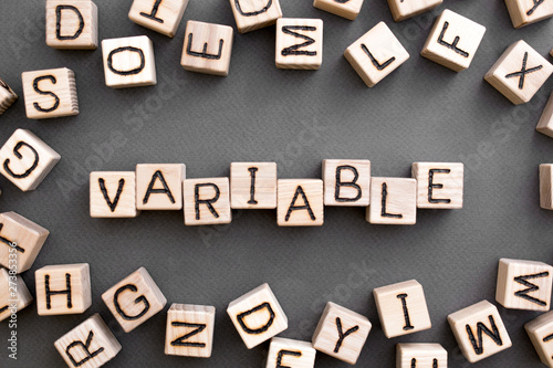 the word variable wooden cubes with burnt letters, variable life, gray background top view, scattered cubes around random letters photo