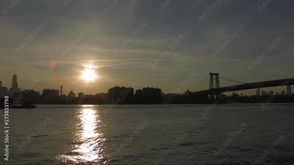 Cityscape of New York City taken from Brooklyn at the end of the day with lens flare and silhouette buildings. Sun Reflection on the water. Brooklyn bridge at right. Cityscape of New York City taken from Brooklyn at the end of the day with lens flare and silhouette buildings. Sun Reflection on the water. Brooklyn bridge at right.