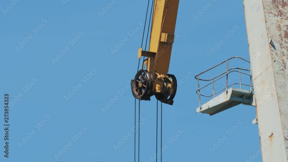 The mechanism of a cargo crane, located in the seaport, against a blue sky. The mechanism of a cargo crane, located in the seaport, against a blue sky.