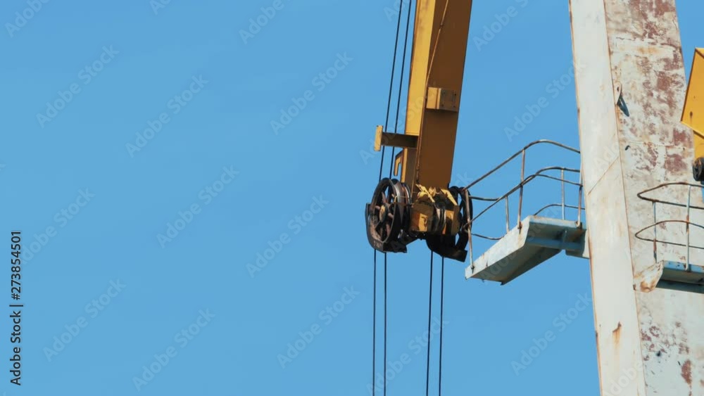 The mechanism of a cargo crane, located in the seaport, against a blue sky. The mechanism of a cargo crane, located in the seaport, against a blue sky.