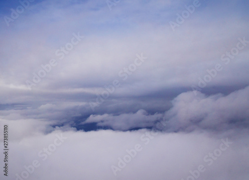 View of the clouds and sky from an airplane. The sun is shining because of the clouds. Flying at a huge height above the ground and the sea.