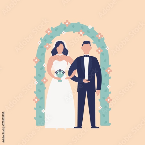 Happy cute newlywed couple standing against floral arch