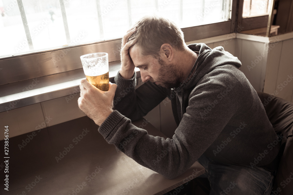 Alcoholic depressed man drinking in a bar feeling sad hopeless a