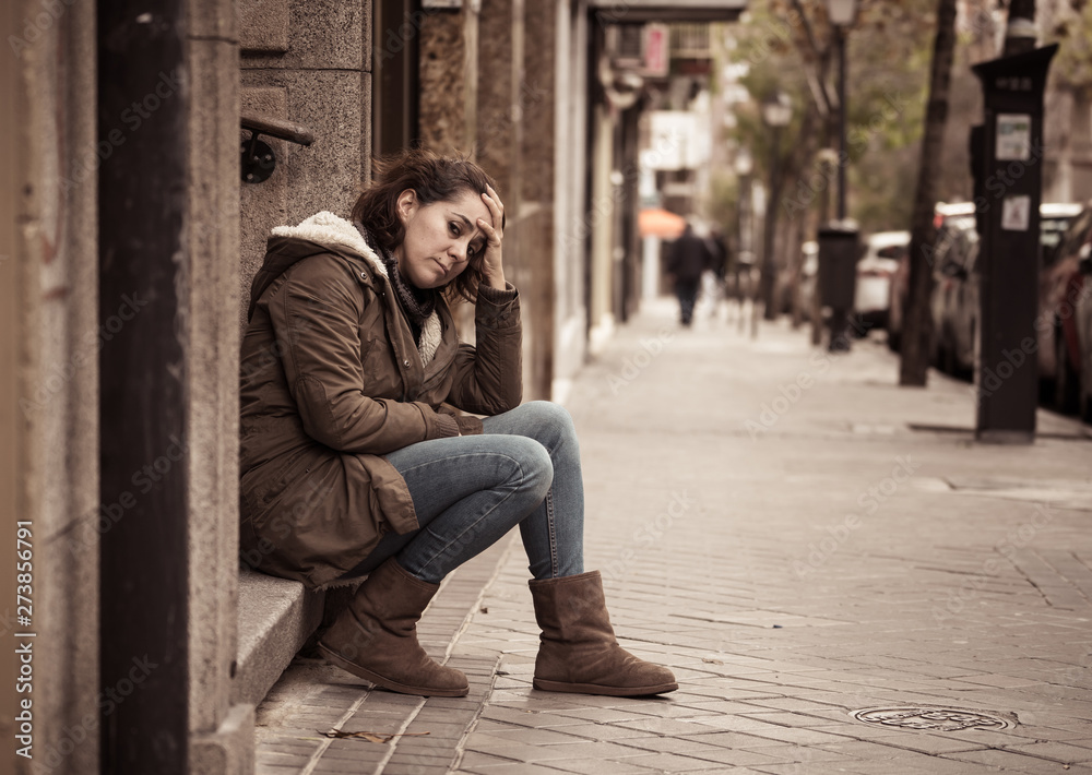 Depressed woman sitting on urban city street overwhelmed and hop