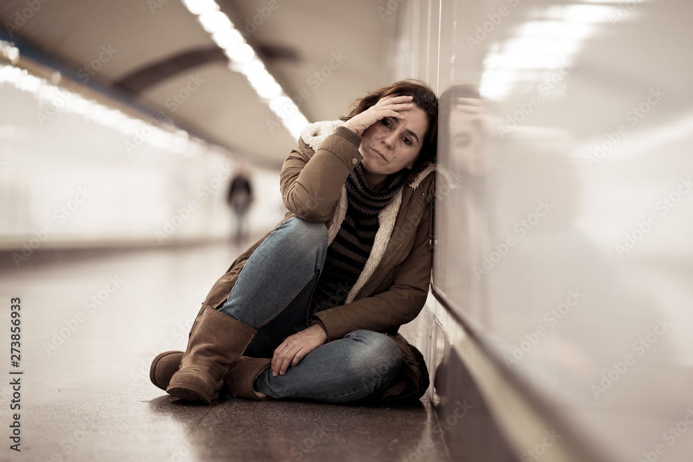 Young desperate adult woman sitting on the ground on subway unde Young desperate adult woman sitting on the ground on subway unde