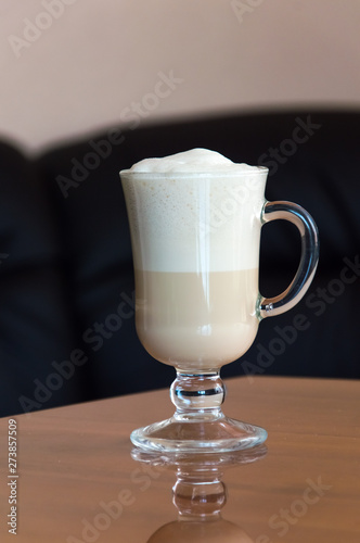 A cup of coffee standing on a wooden office table.