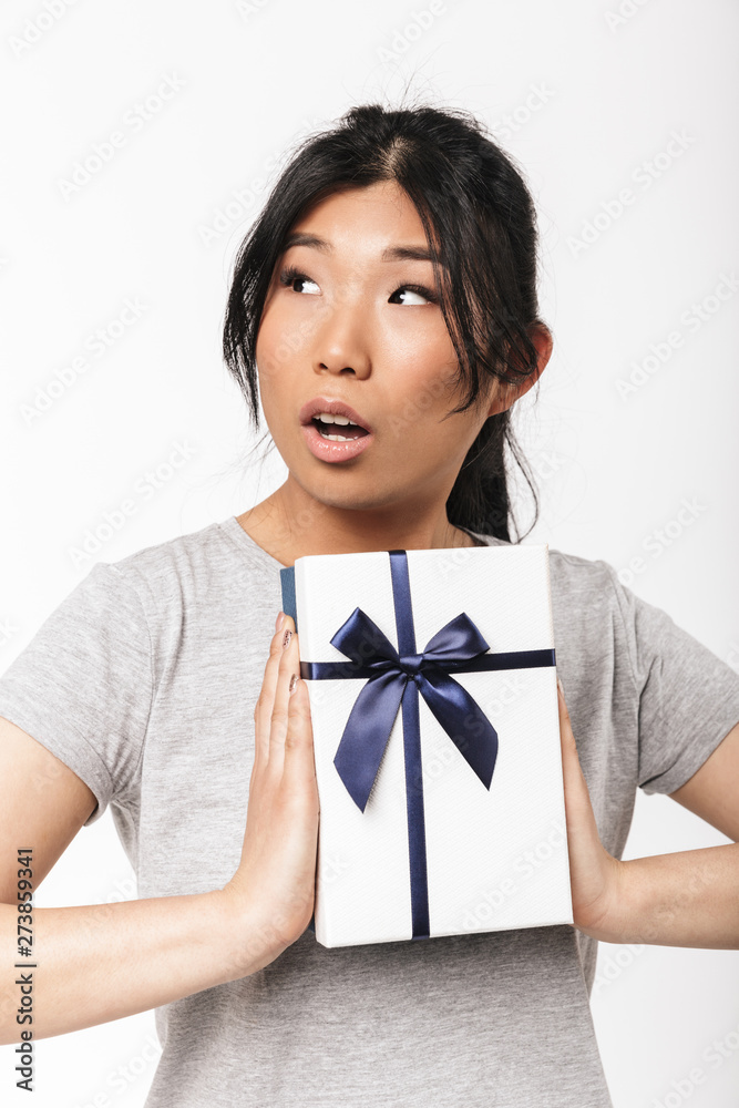 Beautiful young woman posing isolated over white wall background near present gift box. Beautiful young woman posing isolated over white wall background near present gift box.