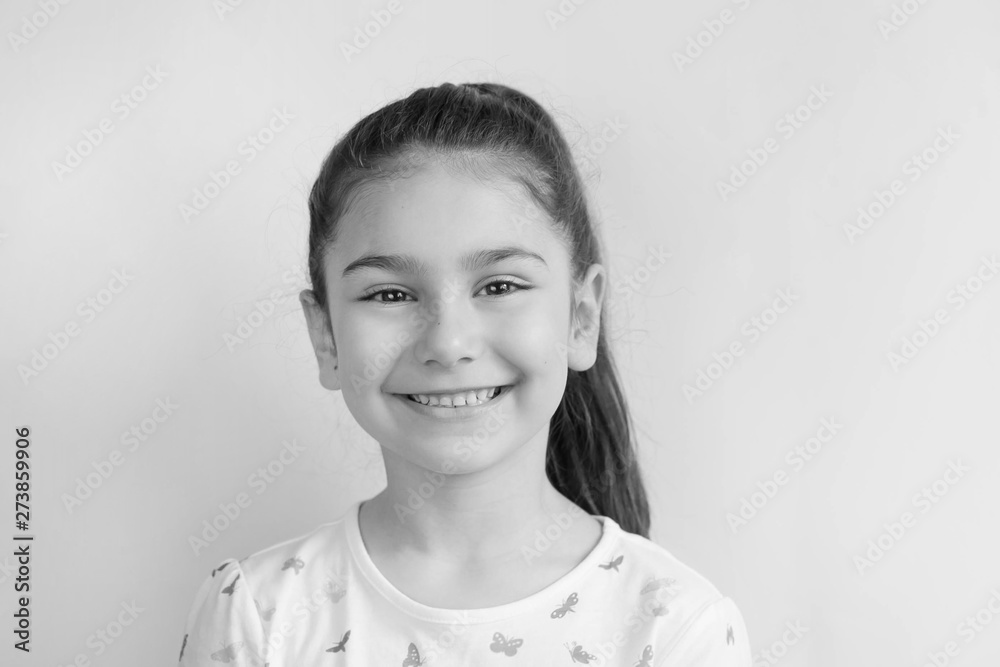 Portrait of happy smiling child girl on light background. Positive emotions. Black and white image. Portrait of happy smiling child girl on light background. Positive emotions. Black and white image.
