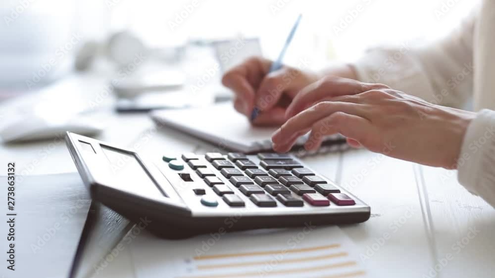  The hands of an accountant work on a calculator and prepare a financial report.