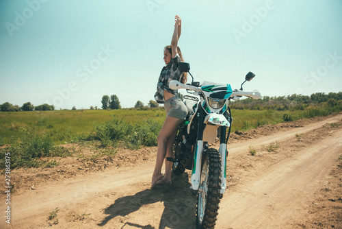 Young beautiful girl posing next to a motorcycle outdoors