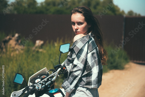 Young beautiful girl posing sitting on a motorcycle outdoors © bo.kvk
