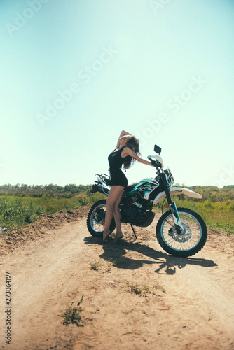 Young beautiful girl posing next to a motorcycle outdoors