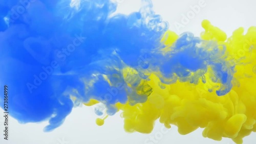 Closeup shoot of yellow and blue watercolor ink splashing and floating in liquid