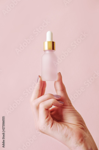 Beautiful groomed woman's hands with serum bottle mock up on a light background.