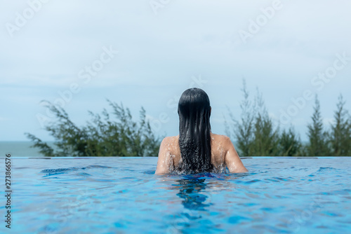 Summer time and Vacations. Women lifestyle relaxing and happy in luxury swimming pool sunbath, summer day at the beach resort in the hotel. Summer Concept