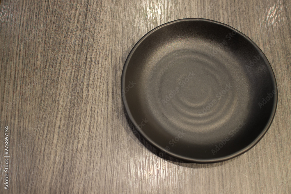 black empty dish on wood table left copy space black empty dish on wood table left copy space