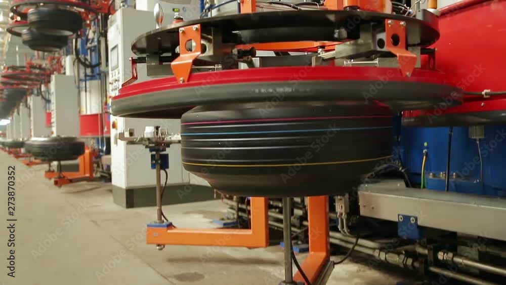 Automated machine feeds tire into tire press. Automotive wheel molding in a factory. Modern automated tire forming tires machine. Car tires automatic building machine in process of tire forming. Automated machine feeds tire into tire press. Automotive wheel molding in a factory. Modern automated tire forming tires machine. Car tires automatic building machine in process of tire forming.