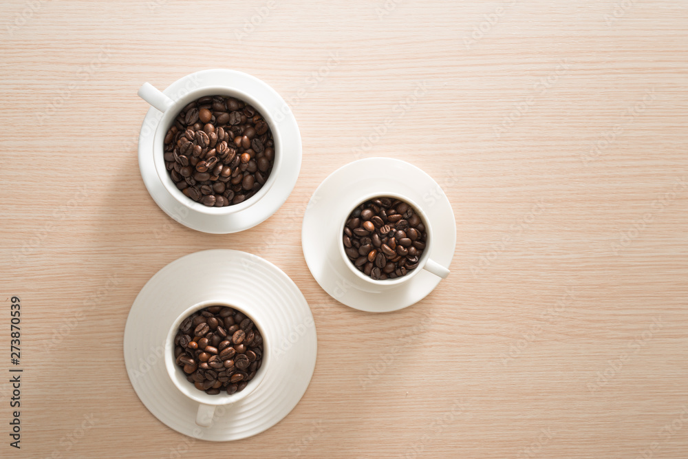 Full coffee beans cups on the wood background Full coffee beans cups on the wood background