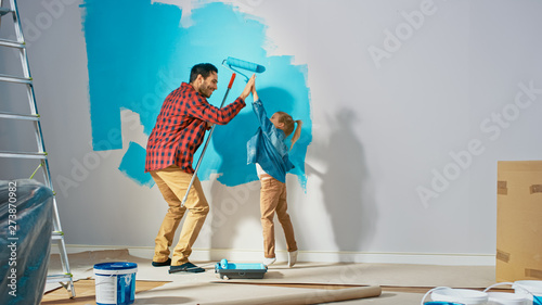 Photography Young Father is Showing How to Paint Walls to Cute Small Daughter