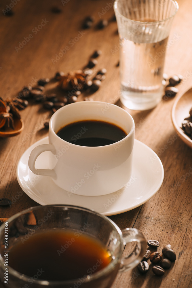 A cup of coffee with water, coffee beans and tea on wooden bakcground A cup of coffee with water, coffee beans and tea on wooden bakcground