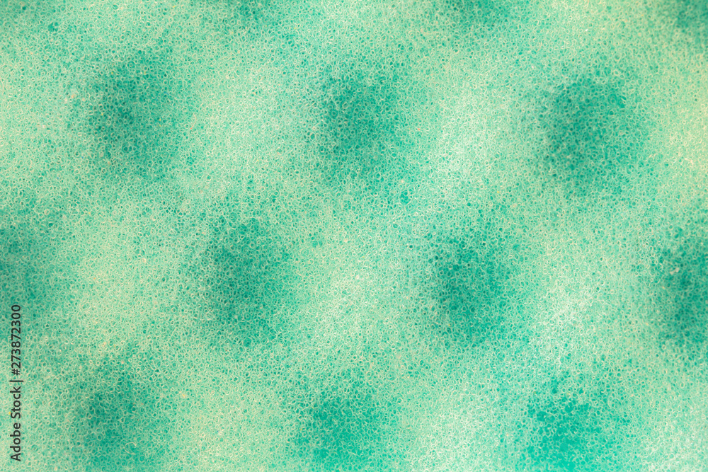 Obraz premium Light green emerald background with a spotty pattern of round shadows. The porous surface of the material under high magnification. Nano and microstructure of a porous sponge under a microscope.