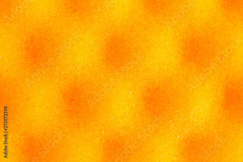Yellow spotted background with round black spots. The pattern on the surface of the sponge porous material. Pores of the material under high magnification. Microscale  macrophotography.