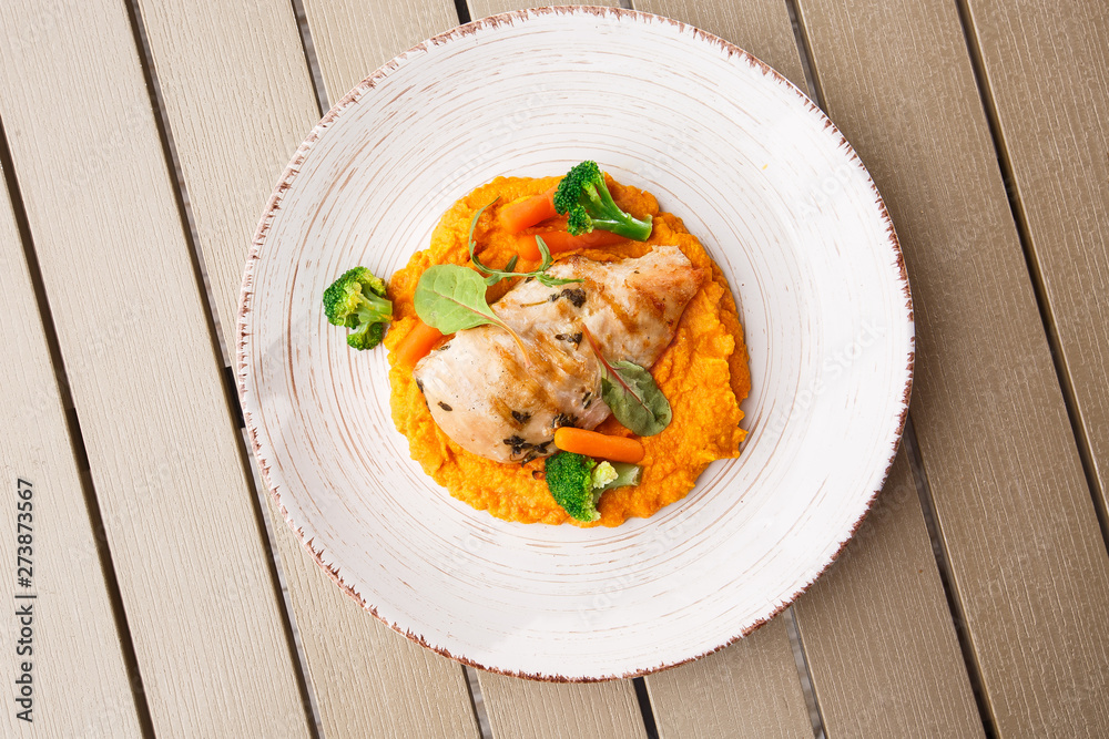 Chicken breast steak with carrot puree baby carrot and broccoli. Grilled chicken slice with baby carrot puree. wooden backgrounf