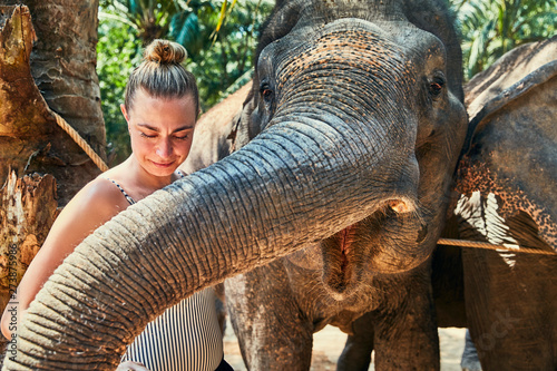 Photography Smiling woman stroking the trunk of a large Asian elephant