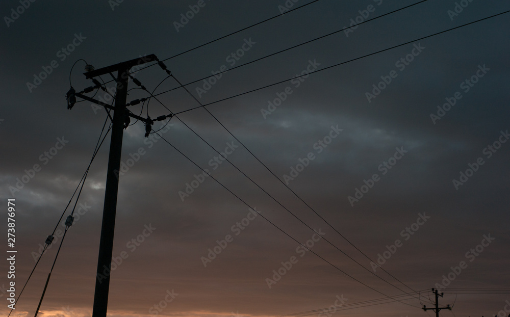 Silhouette of power lines at sunset, dusk cloudy skies Silhouette of power lines at sunset, dusk cloudy skies