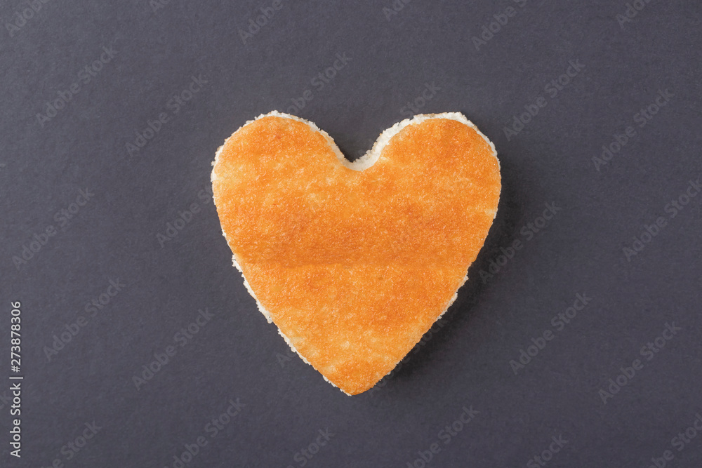 Obraz premium Dessert with a crispy golden crust in the shape of a heart on a plate with a blue border with a wooden fork and spoon