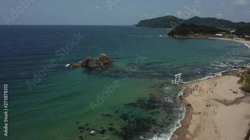 aerial footage of blue ocean, the twin rocks and the white torii gate on the water at the coast of sakurai futamigaura beach, itoshima fukuoka japan, with bird maneuver v08 photo