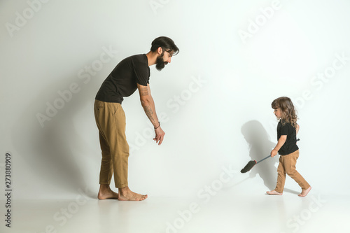 Father playing with young son against white studio background. Young dad having fun with his children in holidays or weekend. Concept of parenthood, childhood, father's day and family relationship.