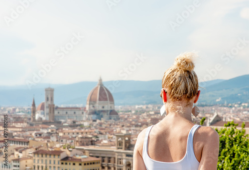 Young woman looking at the city of Florence from the viewpoint. Back view. Empty space for text