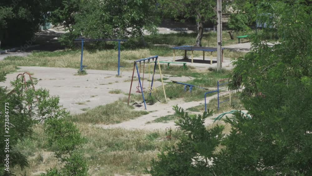 Swings swinging on a large empty playground in the yard closeup Swings swinging on a large empty playground in the yard closeup