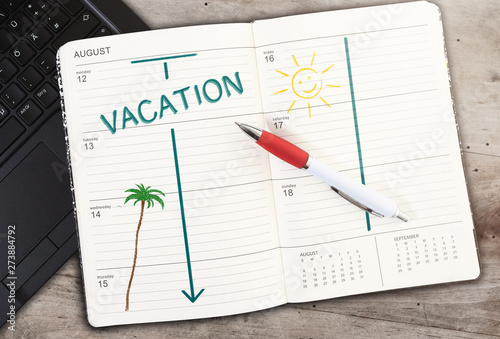 top view of calendar on table with word VACATION and sun icon against wooden table