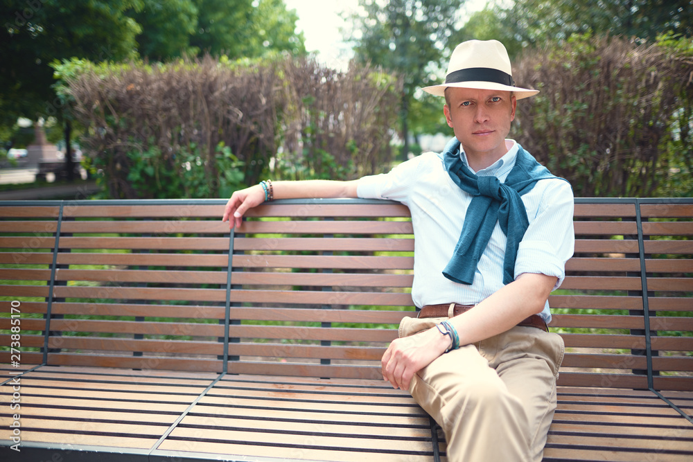 Fototapeta premium Portrait of a guy sitting on a park bench