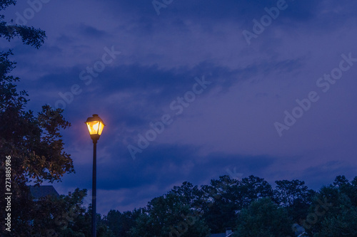 Single lone street light lamp post at night shining in the dark in the evening
