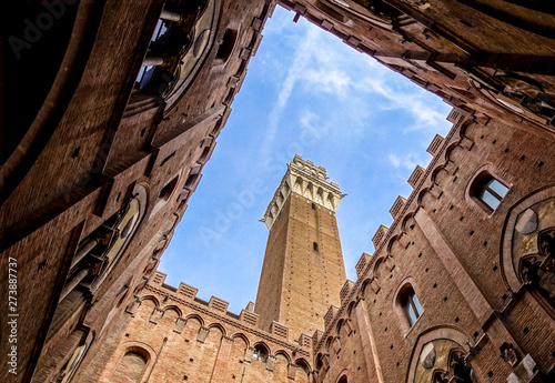 View from the courtyard of Siena town hall Palazzo Pubblico to Mangia Tower Torre del Mangia and blue winter sky, Tuscany, Italy