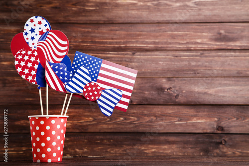 American flag in paper glasses, bow tie and balloons on brown wooden table