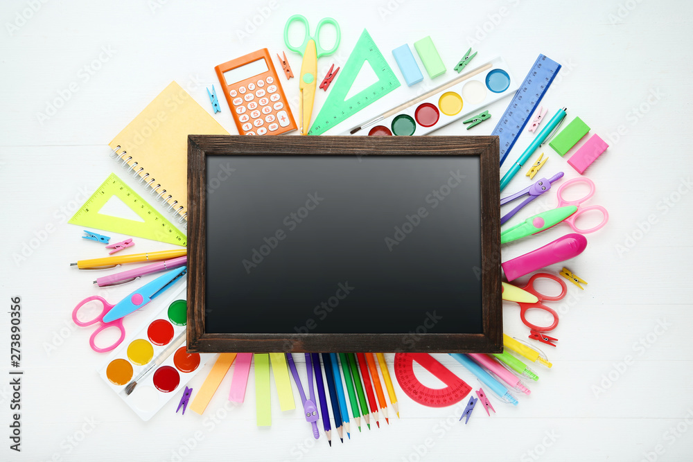 Black frame with school supplies on white wooden table Black frame with school supplies on white wooden table