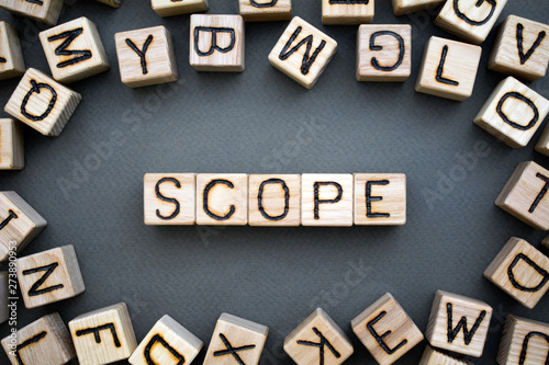 the word scope wooden cubes with burnt letters, scope of activity, gray background top view, scattered cubes around random letters