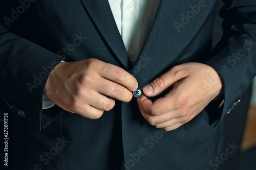 Close up of a man in suit tying a button on the jacket