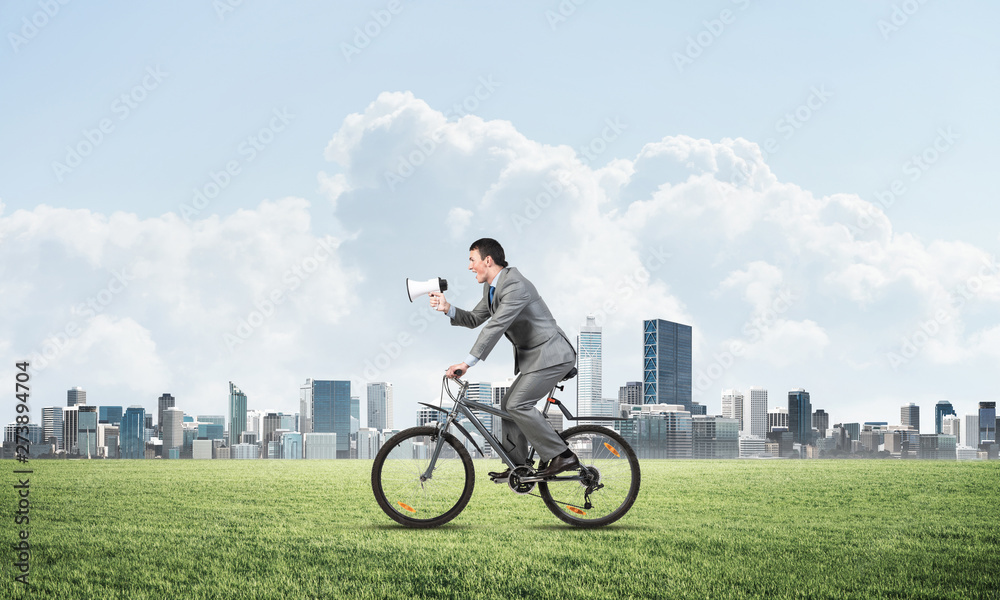 Obraz premium Businessman with megaphone on bike