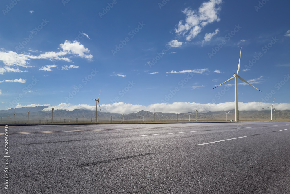 empty asphalt road with nobody and wind turbines for clean energy.