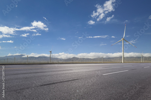 empty asphalt road with nobody and wind turbines for clean energy.