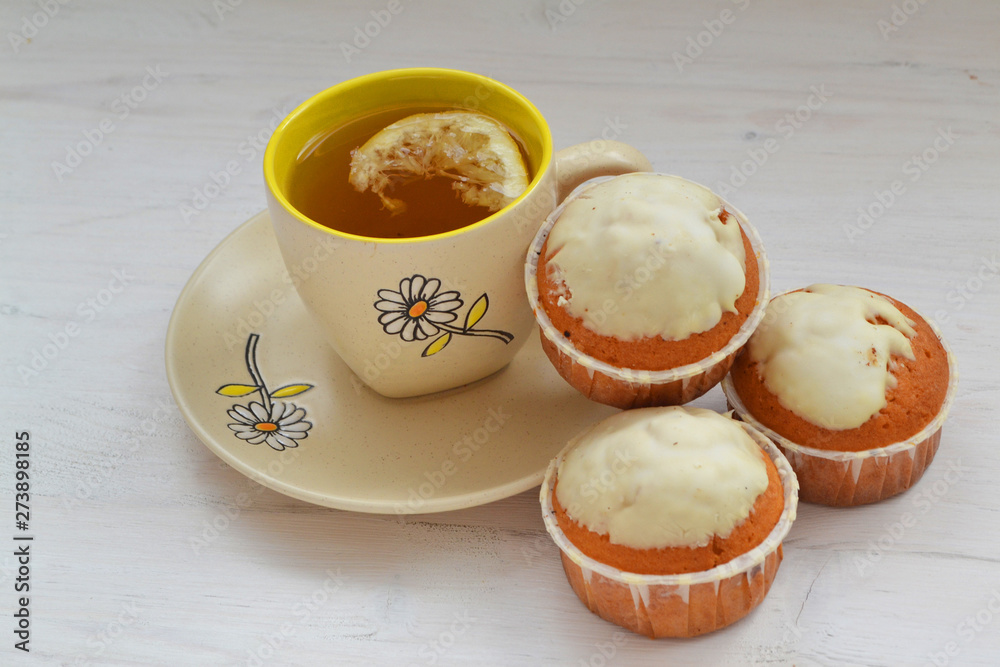 Sweet cupcakes on shabby wooden table with cup of tea Sweet cupcakes on shabby wooden table with cup of tea