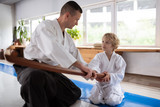 Blonde-haired little boy listening to his aikido teacher